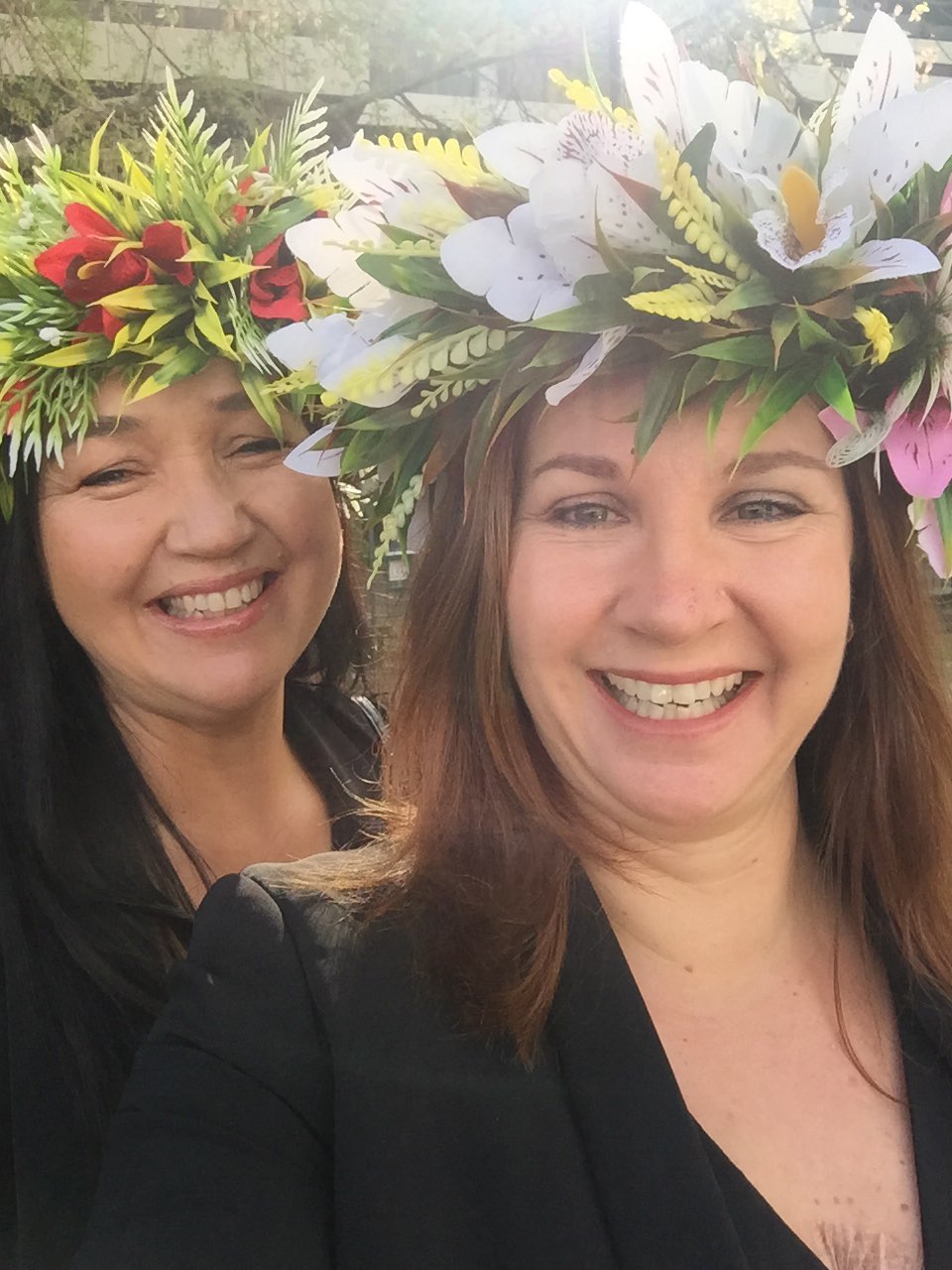 Two women wearing floral crowns smiling at the camera.
